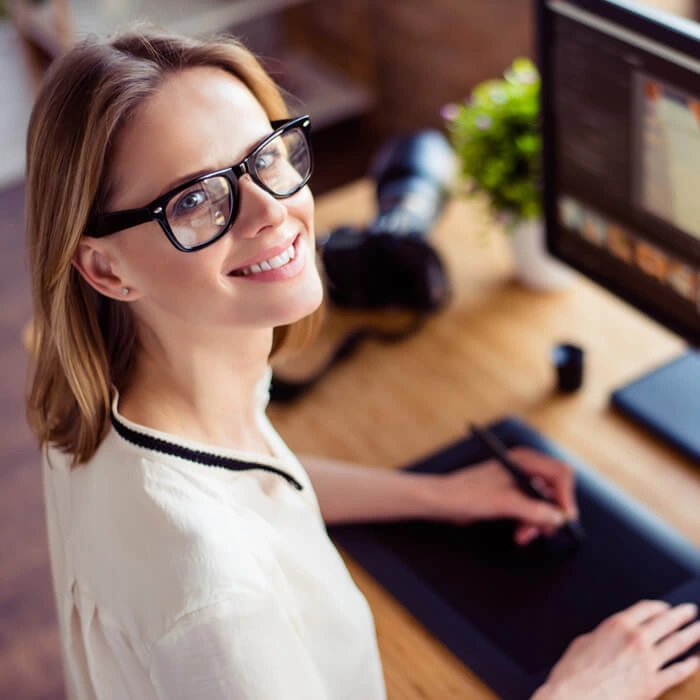 Smiling graphic designer browsing images on desktop computer in creative office space
